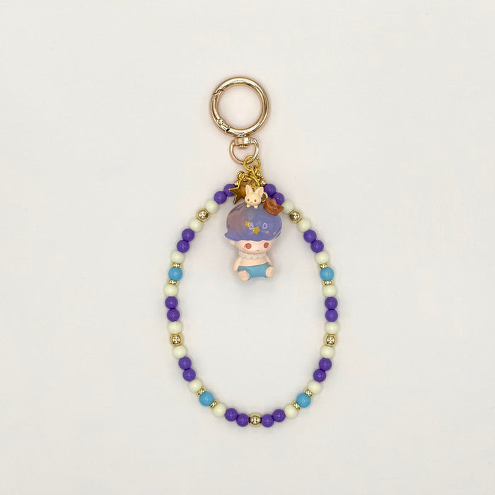Beaded keychain with a small figurine on a light gray background