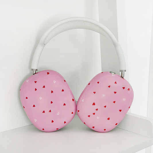 Pink AirPods Max case with red and white hearts pattern on a white shelf.