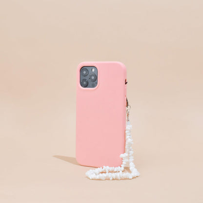 Pink smartphone case with clear Crystal Phone Strap stands upright against a beige background.
