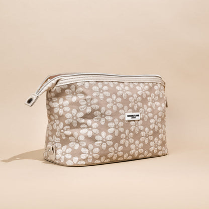 Beige expandable makeup bag with floral pattern and zipper, shown on a matching beige background.