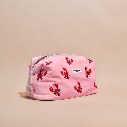 Expandable makeup bag with red lobster print on beige, pink velvet trim, and Coconut Lane branding.