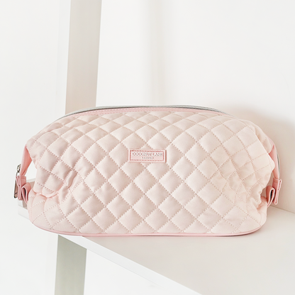 Coconut Lane quilted pink expandable makeup bag displayed on a white shelf.