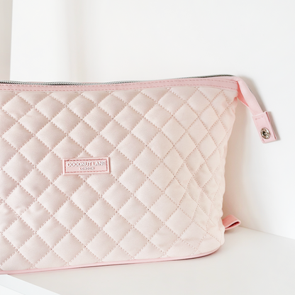 Quilted marshmallow pink expandable makeup bag by Coconut Lane with a zipper, displayed on a white surface.
