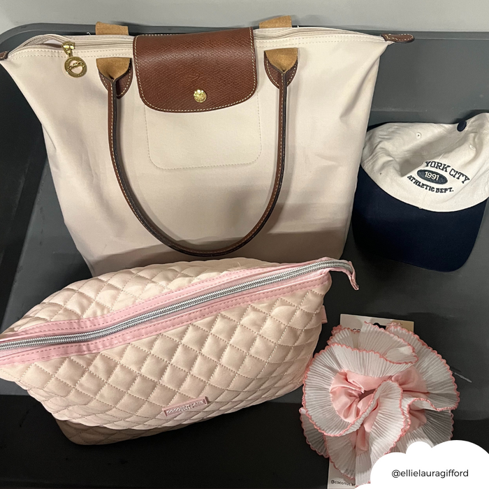 Cream Longchamp tote, quilted pink makeup bag, floral scrunchie, grey NYC 1991 cap.