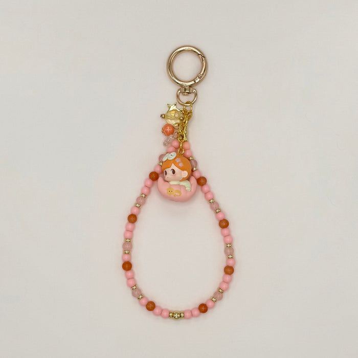 Beaded keychain with a small figurine on a light gray background