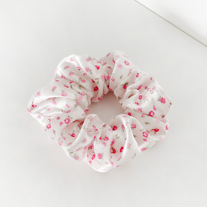 Pink scrunchie with soft, stretchy fabric featuring a pink and red watercolor floral pattern.