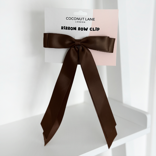Chocolate satin ribbon bow hair clip with long tails, displayed on a white Coconut Lane branded card.