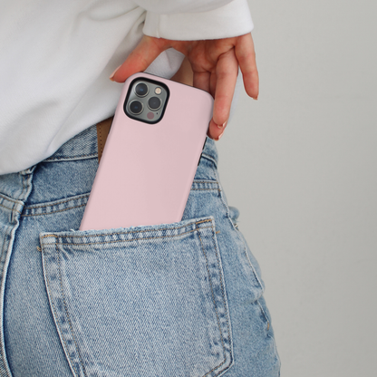 A pink tough phone case is slipped into blue jeans by someone in a white sweatshirt.