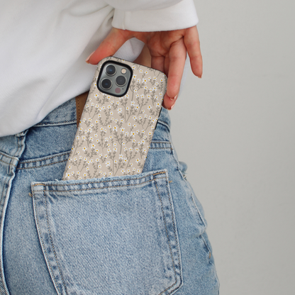 Nude floral MagSafe phone case partly tucked into the back pocket of light blue jeans.